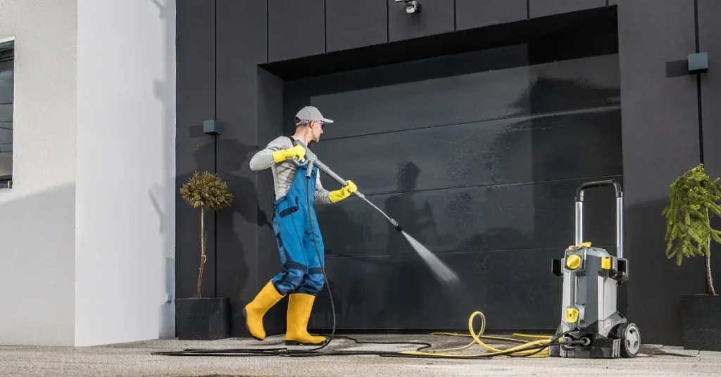 Residential glass cleaning technician power washing a modern home’s exterior black garage window