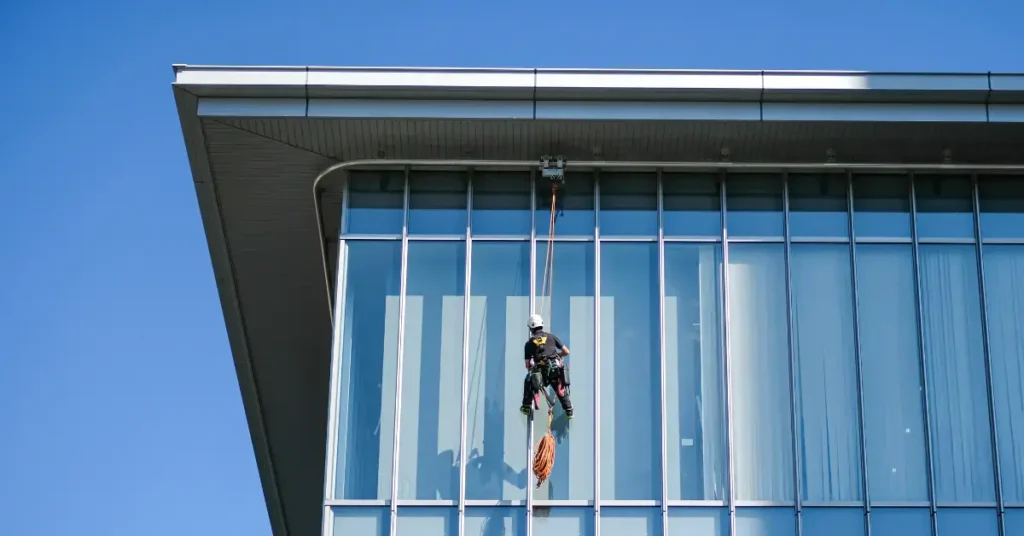 Property pre-sale cleaners using rope access to wash tall building windows.